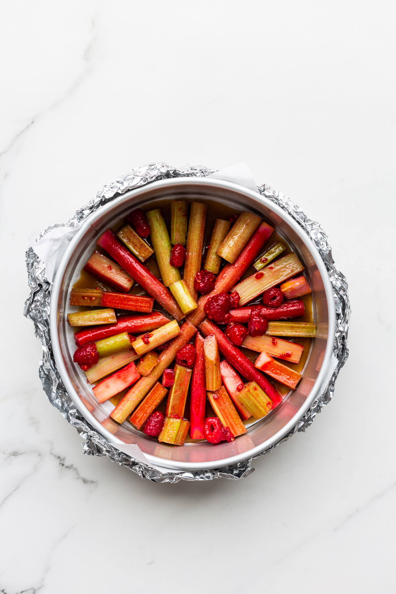 Arranging rhubarb pieces at the bottom of a springform wrapped in foil to make upside down cake