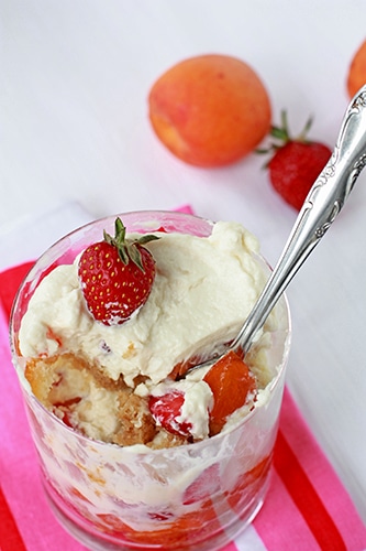 Portion of trifle in a glass with layers of berries, cake, and cream